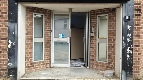 Trevor Snaith/Wycombe Food Hub The building entrance to where the food hub will be based is in a poor state of repair, with visible signs of neglect, damage, and litter inside the doorway.