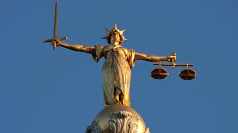 The figure of Lady Justice holding scales in her left hand and a sword in her right on top of the central criminal court in London.