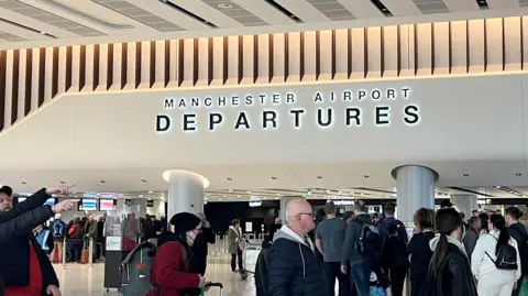 Passengers queue for security screening in the departures area of Terminal 2 at Manchester Airport.