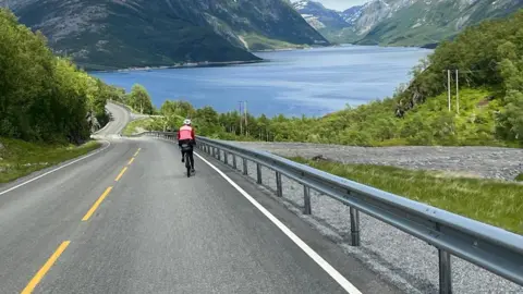 David Stoyle David cycling on a road with the Patagonian mountains in the distance.
