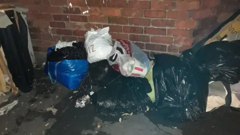 David Wall Shopping bags from QUIZ and KFC rubbish scattered on top of black bags on a street 