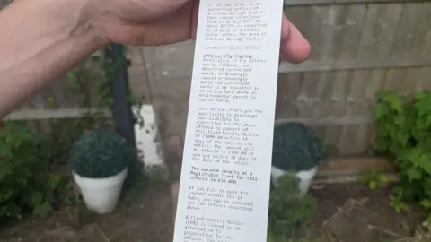 Adam Castledine holds up the fixed penalty notice he received
