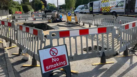 No smoking sign next to gas mains roadworks cordoned off by barriers on Loose Road, Maidstone
