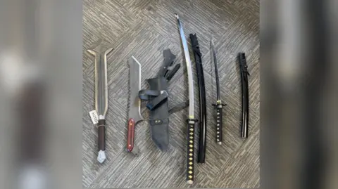 West Yorkshire Police A selection of bladed weapons on a flat surface including a sword