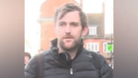 Surrey Police A white man, of slim build, and with short dark hair. He was wearing a black jacket and was carrying a black rucksack.