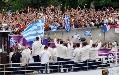   Amanda Perobelli/Reuters Team Greece wave at cheering spectators from their boat on the River Seine during the opening ceremony