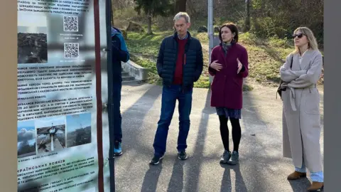 Tove Benefice/Steve Challen A man and two women standing on tarmac with grass and trees behind