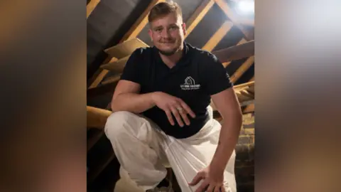 Samuel Szymczyk A man crouched down in a loft