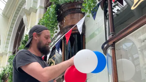 Shaun Whitmore/BBC Man hanging balloons in arcade