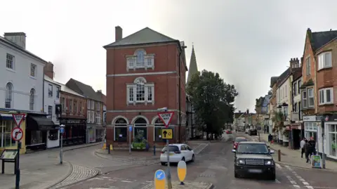 The centre of Market Harborough with a mix of red brick and white-walled buildings on either side of the road