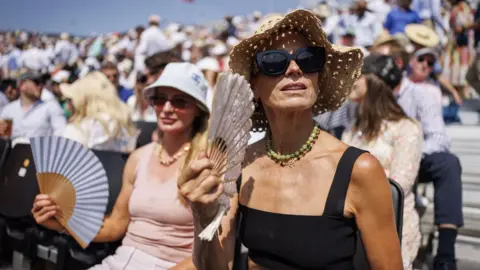 Spectators use fans to cool down at the Queen's Club Championships tennis tournament in London, Britain, 19 June 2025