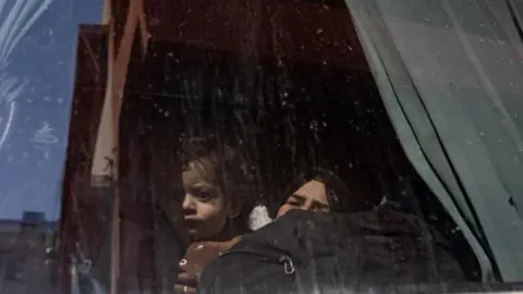 EPA-EFE/REX/Shutterstock A woman and a child peer through the window of a bus heading through the Rafah crossing. 