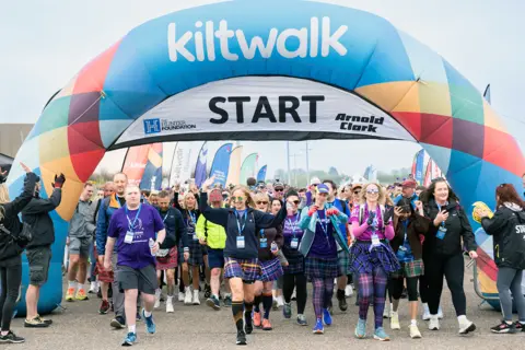 Elaine Livingstone A group of walkers setting off through an inflatable arch at the start of the Kiltwalk