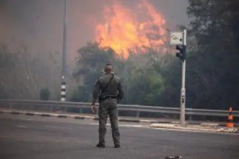 A security officer watches as wildfires burn in Israel