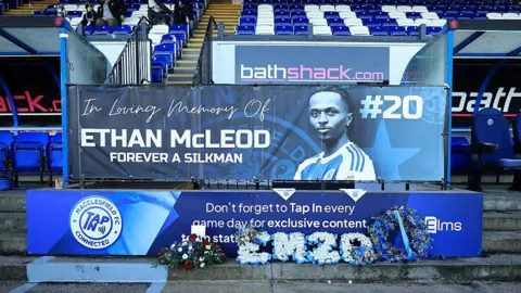 Getty A memorial banner dedicated to Ethan McLeod at Macclesfield FC's stadium. Featuring his photograph, the predominantly blue banner has the words in writing writing: "Ethan McLeod Forever A Silkman".