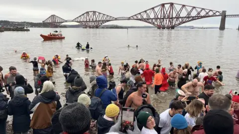 Dozens of people are in the Firth of Forth in varying fancy dress costumes.