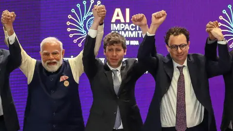 AFP via Getty Images India's Prime Minister Narendra Modi stands beside Sam Altman and Dario Amodei, shown clenching their fists instead of holding each other's hands, at the AI Impact Summit in New Delhi in February.