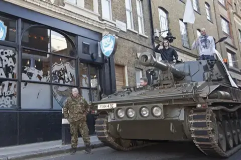 Brewdog A tank outside a Brewdog bar in Camden.A man in military uniform stands next to the tank, while two men stand on the top of the vehicle.