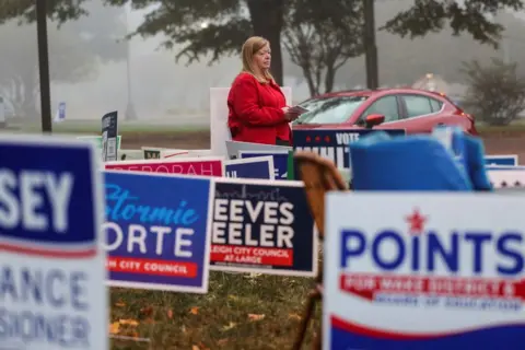 Sam Wolfe/REUTERS A woman stands near a polling station in Raleigh, North Carolina, 5 November 2024 