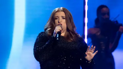 BBC/Hungry McBear/Gary Moyes A woman sings on a well-lit stage