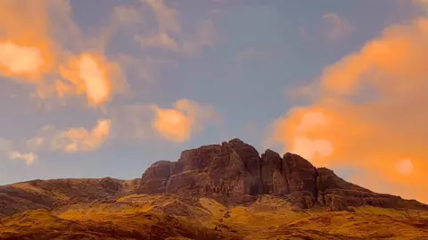 Lavanya Kashyap Una montaña bañada por la luz roja del atardecer.