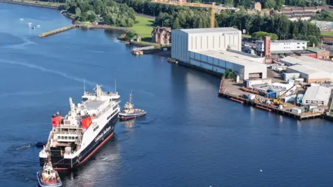 Christopher Brindle A large ferry is pulled by tugs towards a shipyard