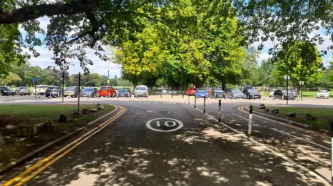 Hull City Council A road with road markings and bollards, with cars and trees in the distance.