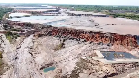 Associated Press Aerial showing path of tailings dam having breached into the environment. Mud residue has covered a vast area in the foreground of the image.