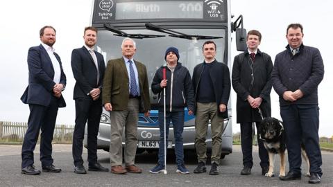 Left to right, standing in front of a bus, Tim Rivett General Manager RTIG-INFORM, Ben Maxfield Go North East Business Manager, Glen Sanderson Northumberland Council Leader, Phillip Ward who is visually impaired, Chris Theobald, Senior Policy Public Affairs and Campaigns Manage