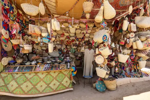 AHMAD HASABALLAH/GETTY IMAGES Man stands in the middle of an exhibition stall stocking several bags...