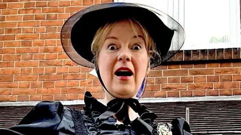 A woman with a shocked face dressed in clothes from the 19th Century.