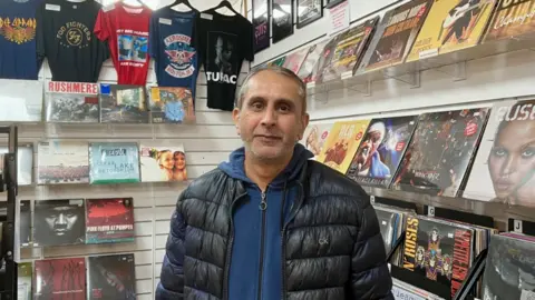 BBC Man sourit à la caméra tenant un record derrière lui.