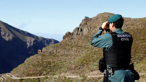 Reuters A Guardia Civil officer peering into a ravine with binoculars