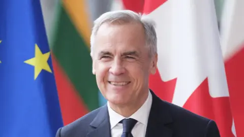 A close up of Mark Carney with the Canadian and EU flags in the background