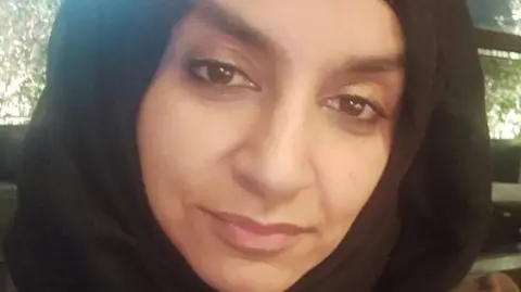 Syira Ahsan A selfie taken by Dr Syira Ahsan, who is offering a slight smile to the camera and is wearing a dark head covering.