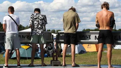 Men stand at urinals at a festival