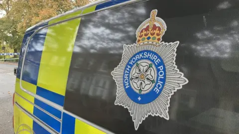 Image of North Yorkshire Police logo on blacked out window of Police van.