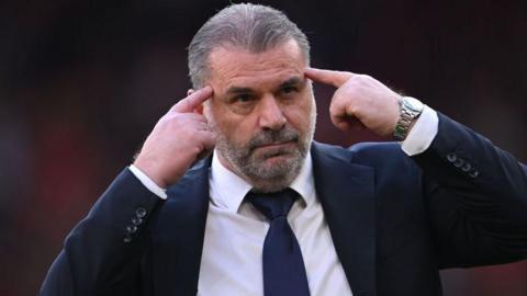 Ange Postecoglou points to the temples of his head during their Premier League fixture against Liverpool