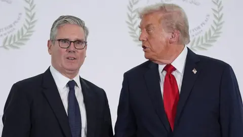EVAN VUCCI/POOL/AFP via Getty Images Starmer, in dark blue tie, faces forward as Trump, in bright red tie, stands next to him, talking to him side on. 
