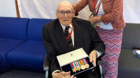 Boyd Salmon is holds a box containing four or five medals following a ceremony at the Royal Navy's base in Portsmouth