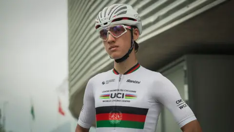 Fariba wearing cycling kit, glasshes and a helmet looking into the distance