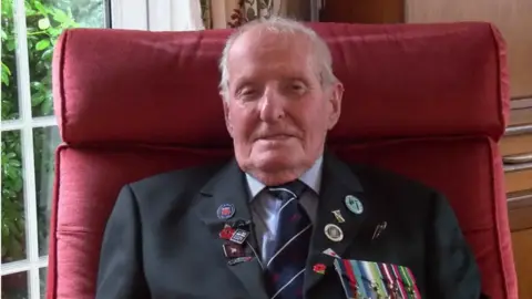 BBC 98-year-old Norman Bartlett in a shirt, tie and jacket with medals on the outside pocket