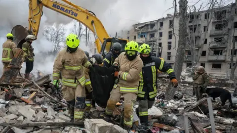 Reuters Rescuers carry a bag with the body of a person found under debris
