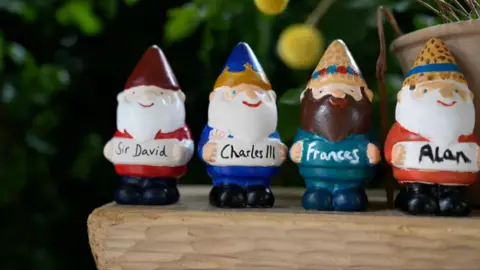 Four garden gnomes with Sir David, Charles III, Frances and Alan written on them.