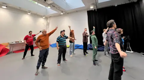 Large room with an open space with a group of people dancing in the middle