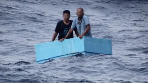 Two men inside a cooling box in the middle of the sea