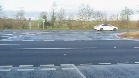 Google A street view of the road junction where the crash happened at Ingleby Arncliffe. There is a give way line, beyond which are two lanes, then a central turning area and two lanes beyond with trees and fields in the distance.