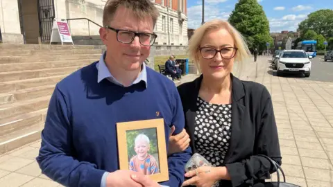 Mark Neillings and Stephanie Neillings holding a picture of Oscar