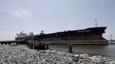 James Cooke/BBC The vast Minerva Gloria oil tanker docked at a wharf in the Mississippi Sound