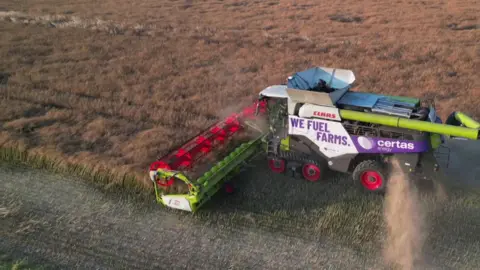 A large plough machine ploughs the land on a sunny day.